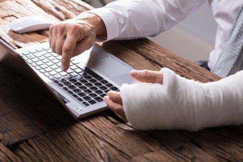 man typing on computer with hand in a cast